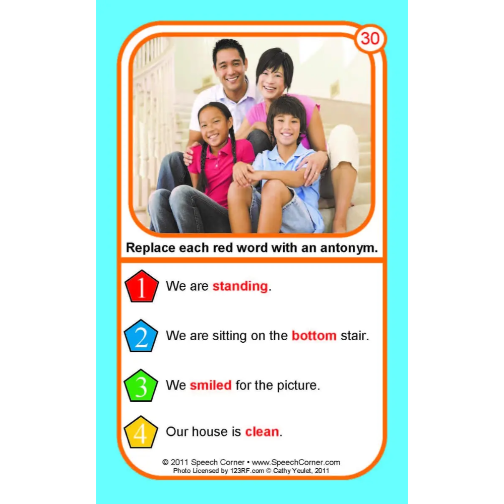 A printed educational card with a family photo at the top and text exercises below, including sentences with red words to be replaced by antonyms. The card is centered on a light blue background.