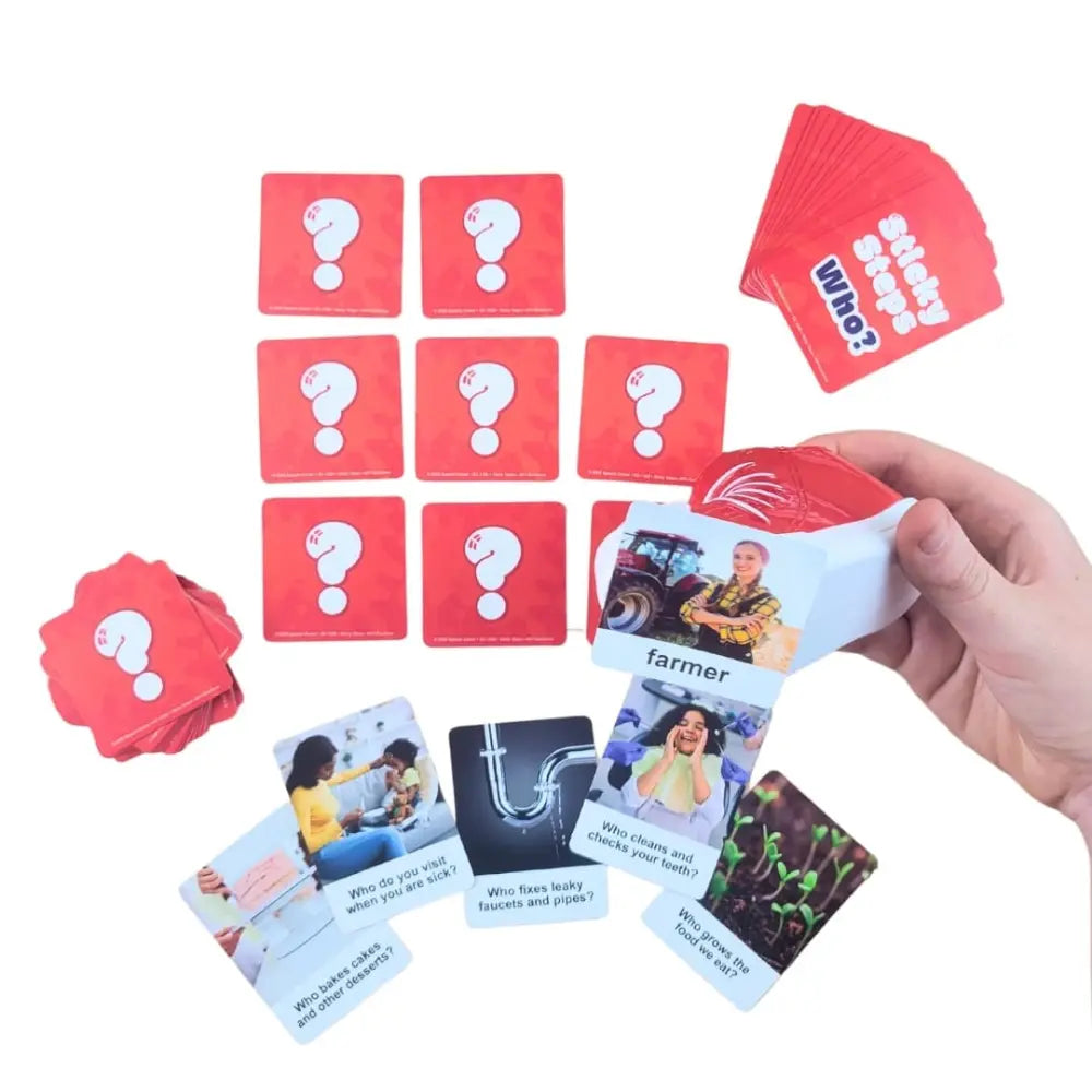 A hand holding a deck of red and white mystery cards, with multiple red question cards and several example cards fanned out on a white background.