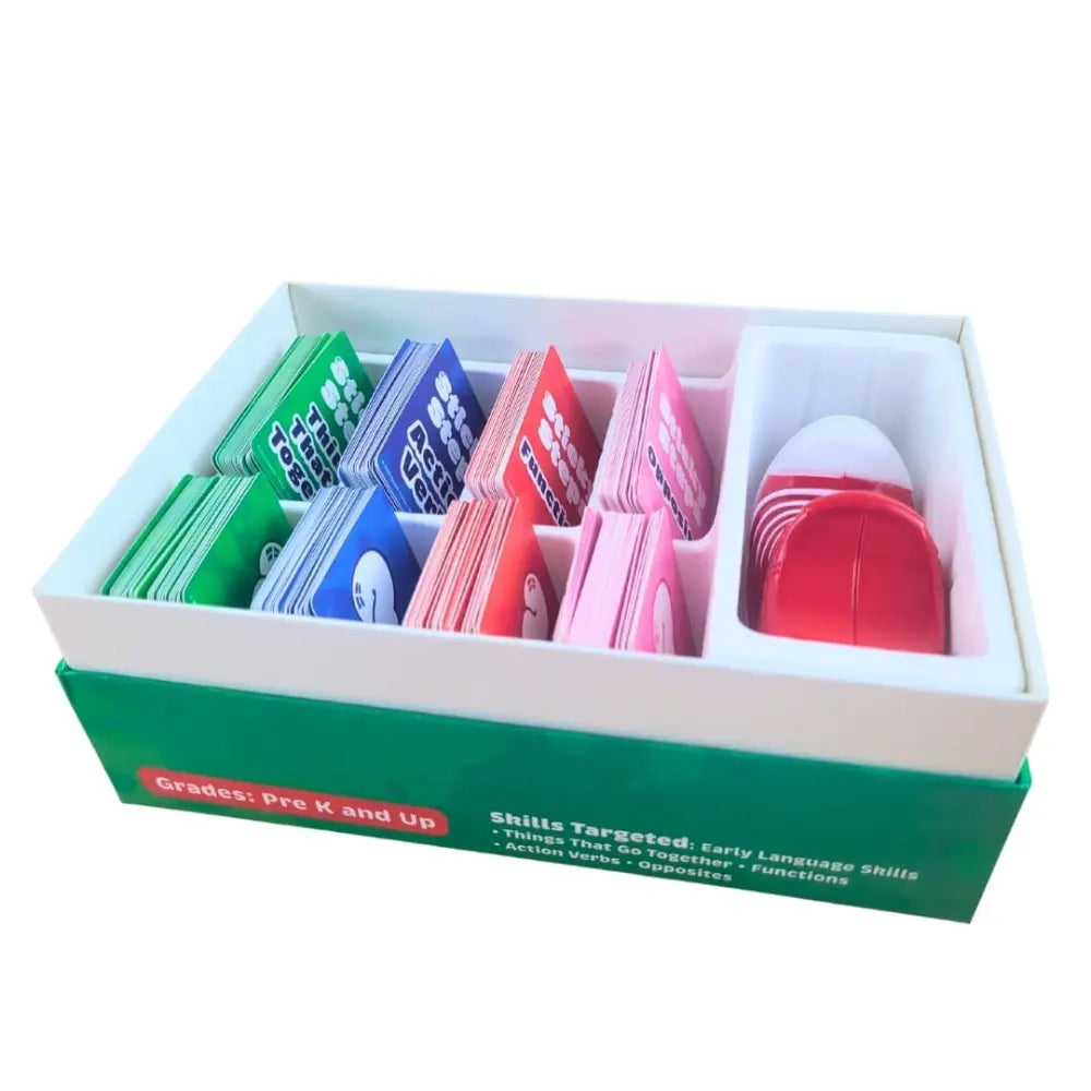 A boxed educational card set displayed open on a white background. The green and white box contains multiple rows of colorful cards in green, blue, red, and pink, plus a compartment holding red and white pieces.