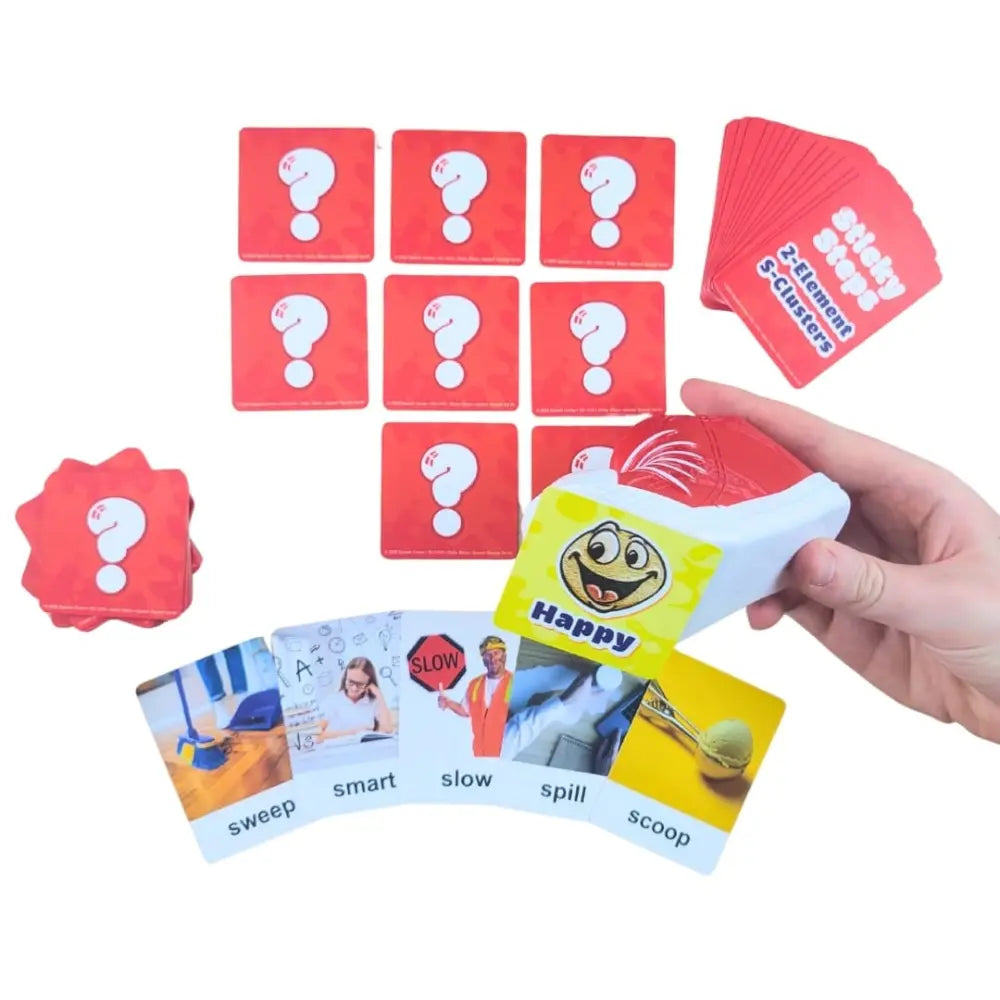 A hand holds a deck of colorful educational flashcards, with several red question-mark cards and a fanned deck of cards visible on a white background. The cards include real-life photos and words such as sweep, smart, slow, spill, and scoop.