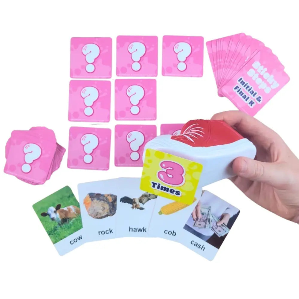 A card game set with pink question cards and several illustrated cards showing cow, rock, hawk, cob, and cash on a white background.