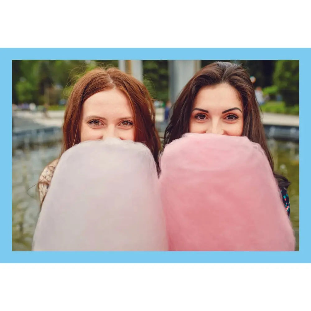 Two women outdoors behind large pink and white cotton candy, with a light blue border around the photo.